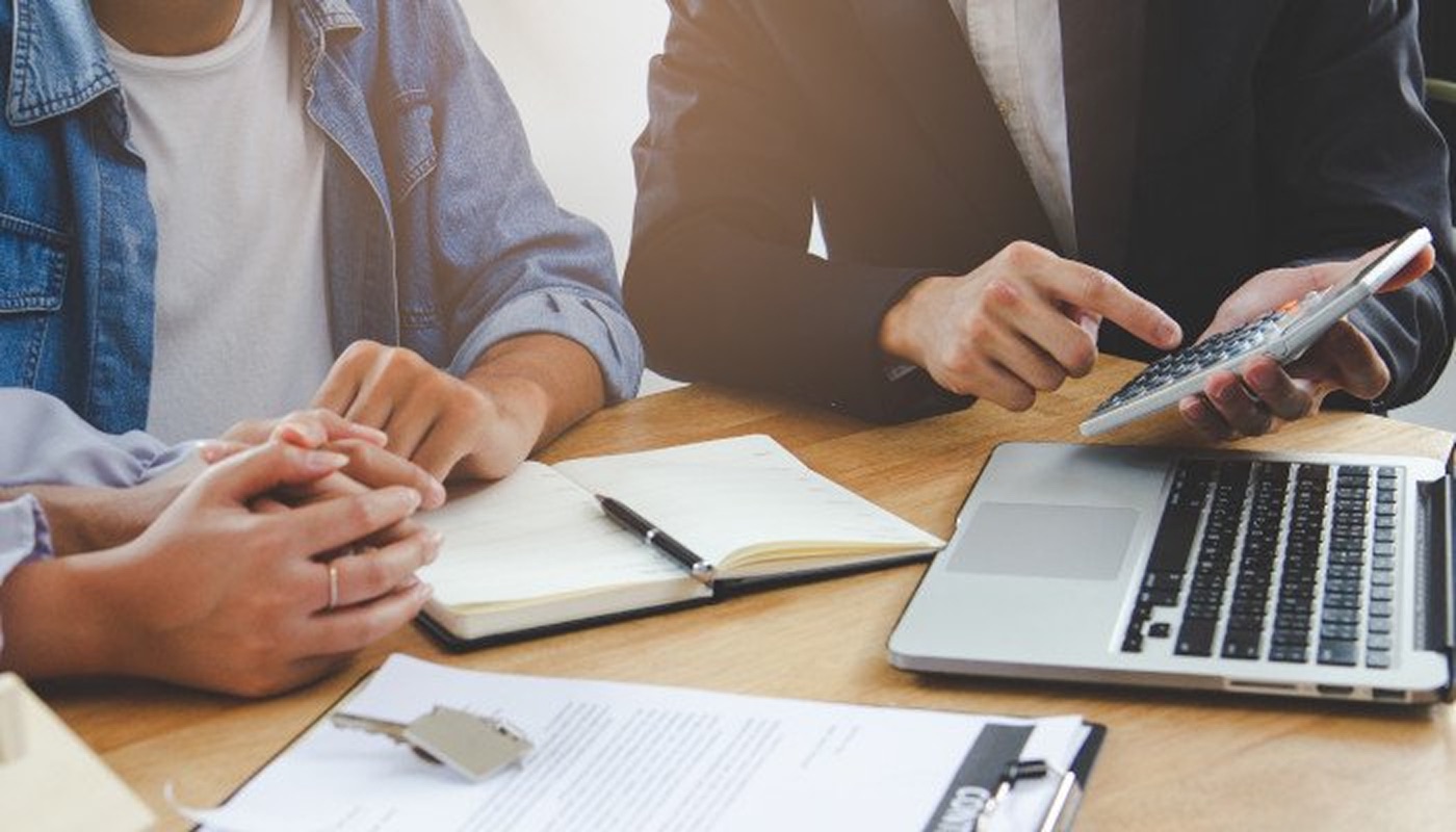 A loan officer reviewing mortgage financing with clients at a desk